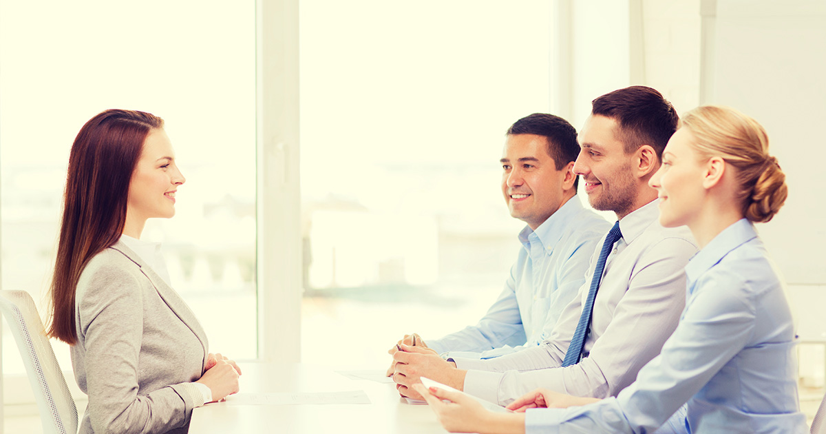 Woman at a desk facing interviewers